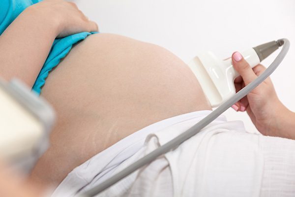 Close Up Pregnant Woman Belly Having An Ultrasound At Doctor's Office