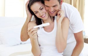Enamoured couple finding out results of a pregnancy test sitting on the bed